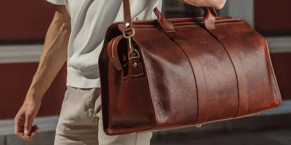 man holding brown leather duffel bag