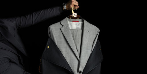 Black leather garment bag held open to show a light gray suit inside.