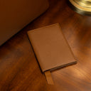 Leather passport holder on a vintage table near an old lamp and a luxury tote bag