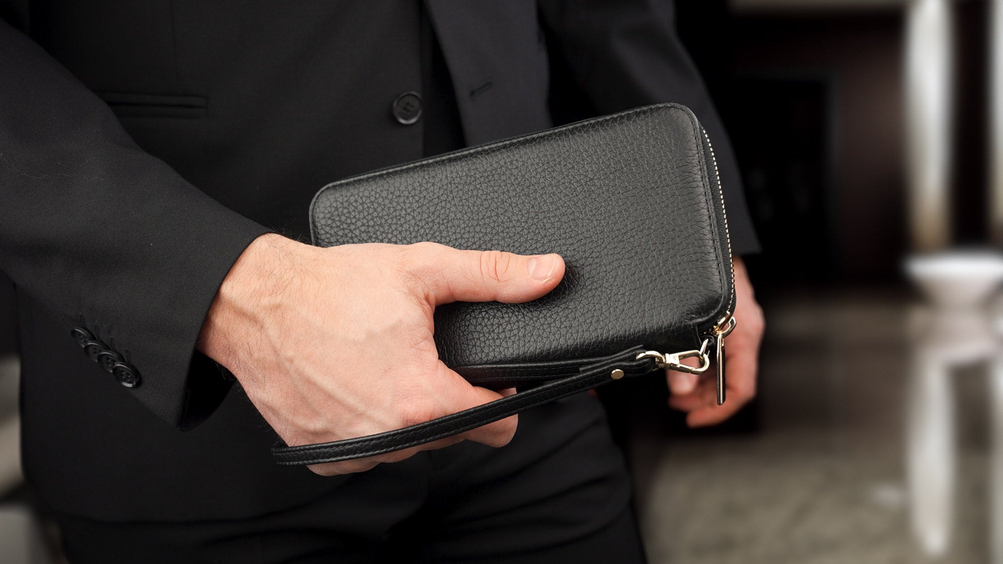 Von Baer W2 luxury RFID men’s leather wallet in black with wristlet, held by a male model.