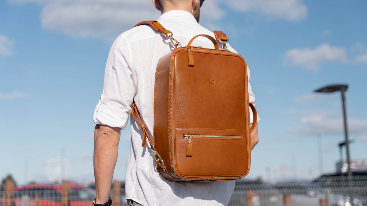 Von Baer full grain vegetable-tanned leather backpack in tan, worn by a male model in a car park