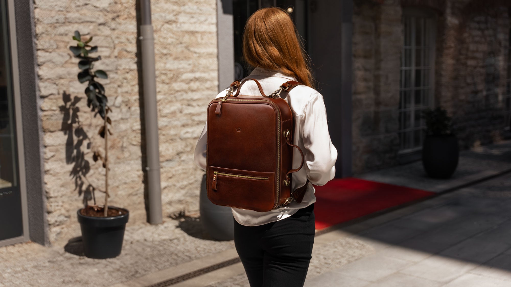 Von Baer 10x luxury leather travel backpack for women, worn by a beautiful female model, slider.