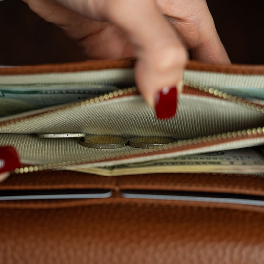 Von Baer Allure large cognac tan full-grain leather accordion wallet, shown in a close-up as a hand with red nail polish opens the coin compartment.