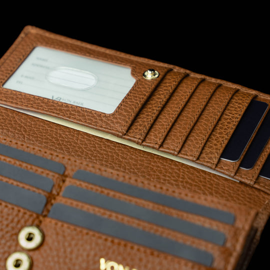 Von Baer Allure large cognac tan full-grain leather accordion wallet with RFID protection, shown in a close-up highlighting its hidden pocket and card slots against a black background.