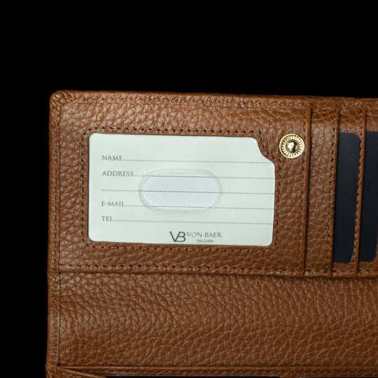 Von Baer Allure large cognac tan full-grain leather accordion wallet with RFID protection, shown in a close-up highlighting the ID window and brand logo against a black background.