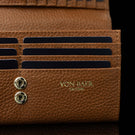 Von Baer Allure large cognac tan full-grain leather accordion wallet with RFID protection, shown in a close-up showcasing front card slots filled with cards and gold-tone branding against a black background.