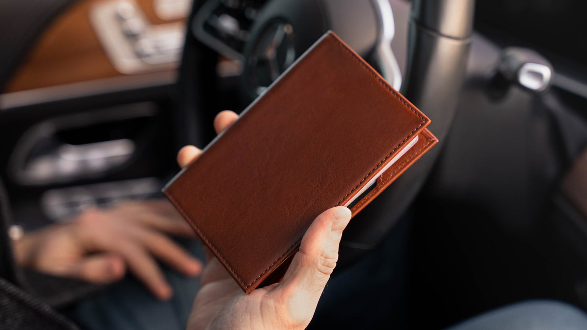Von Baer Atlas full-grain leather passport holder in brown held in hands with cards, luxury travel accessory.