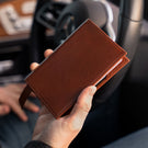 Von Baer Atlas full-grain leather passport holder in brown held in hands with cards, premium travel accessory for professionals.