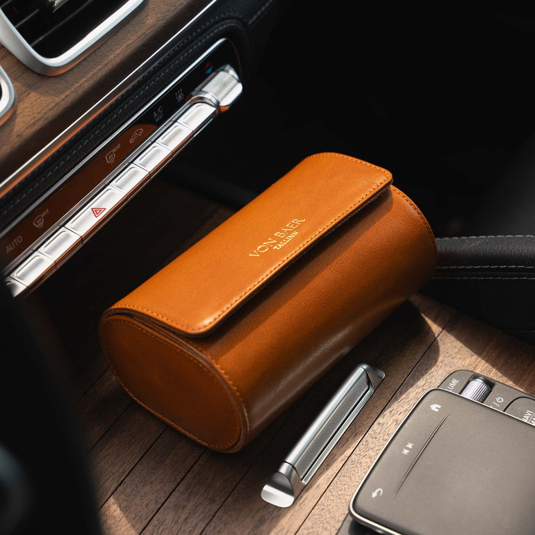 A tan Von Baer Calibre luxury full-grain leather watch roll case with two slots in a Mercedes car.