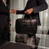 Von Baer City Business Leather Laptop Bag in black, with two well-dressed men shaking hands.