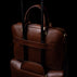 Von Baer City leather laptop bag for travel, showing the back view with a luggage strap on trolley luggage