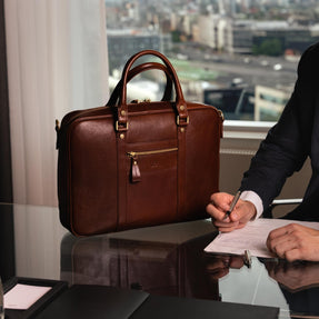 Von Baer City Luxury Leather Laptop Bag in brown, placed in the office near a businessman.