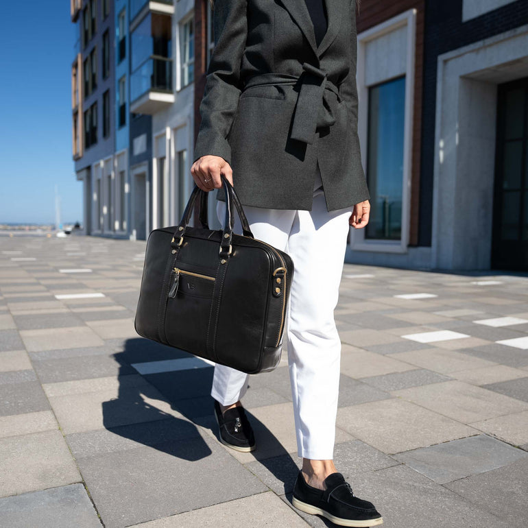 A beautiful woman holding a black Von Baer City luxury leather laptop bag in a city setting.
