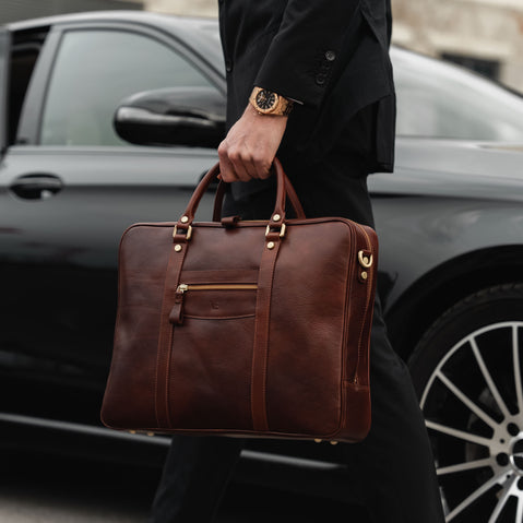 von baer city top luxurious large leather mens laptop bag for work brown carried by man in a suit near expensive car