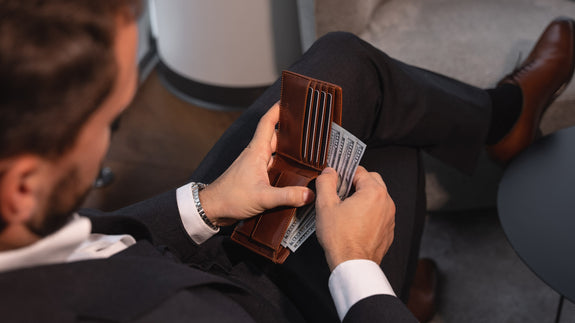 Von Baer Classic bifold Italian leather luxury men's wallet in the hands of a male model with dollars, slider.