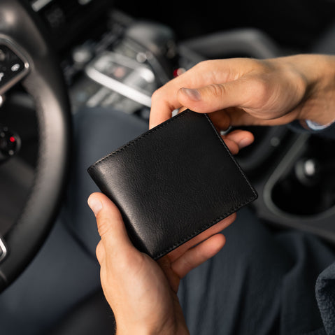 Von Baer Classic compact minimalist bifold leather wallet in black, held in a man's hands