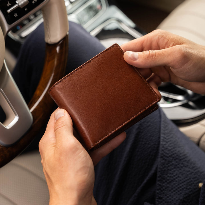 Von Baer Classic bifold leather wallet in brown, held by a businessman inside a car