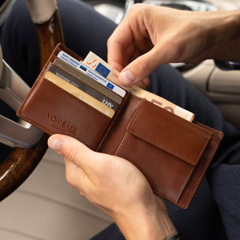 Von Baer Classic bifold leather wallet in brown, stuffed with cash and credit cards, shown with a man taking out euro banknotes
