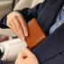 Von Baer Classic bifold leather wallet in tan, removed from a suit pocket by a man inside a car