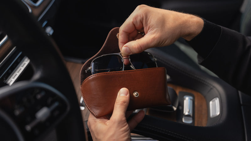 A brown Von Baer Deluxe luxury leather sunglasses and glasses case in a car, with glasses being taken out.