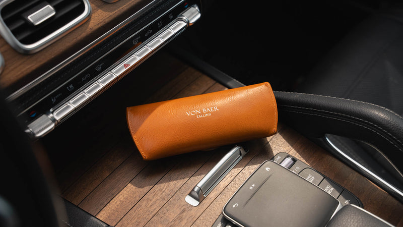 A rear-side view of a tan Von Baer Deluxe luxury leather sunglasses and glasses case on a wooden panel in a car.