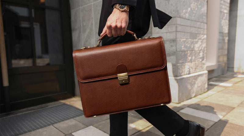 Von Baer Diplomat luxurious premium brown full-grain leather men's briefcase, carried by a man walking in a city setting, highlighting professional style and craftsmanship