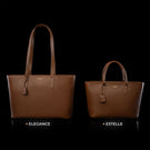 Von Baer Elegance and Estelle women's full-grain leather tote bags in cognac and tan, displayed side by side on a black background to compare sizes, featuring matching top handles, hanging leather tags, and gold-tone logo plaques, with the larger Elegance bag on the left and the smaller Estelle bag on the right
