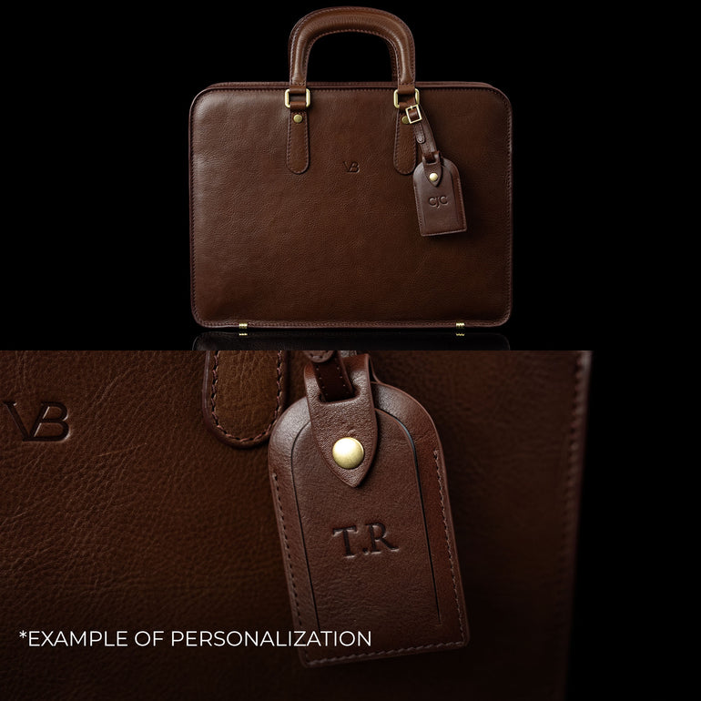An elegant Von Baer leather laptop bag showing an example of personalization with embossed initials on the attached luggage tag.