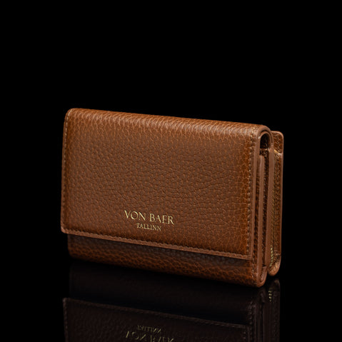 Von Baer Elise women's cognac pebbled leather trifold wallet shown from a three-quarter front view on a reflective black surface, featuring gold-embossed Von Baer Tallinn branding.
