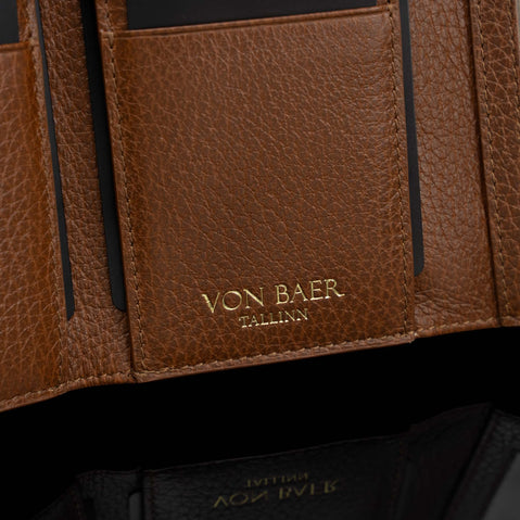 Von Baer Elise women's cognac pebbled leather trifold wallet shown in close-up against a black background, highlighting its interior texture and gold-embossed Von Baer Tallinn branding.
