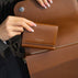 Von Baer Elise cognac tan pebbled leather trifold wallet shown against a matching Isabella Grande large leather crossbody bag, highlighting debossed brand lettering detailing and interior storage.