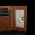 Von Baer Elise women's cognac pebbled leather trifold wallet displayed open on a black background, showing card slots, an ID window with snap closure, and embossed Von Baer Tallinn branding.