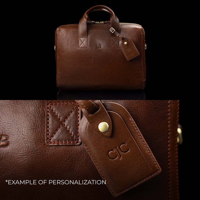 A Von Baer Essential leather laptop bag, showing an example of personalization with embossed initials on the attached luggage tag.