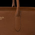 Close-up of a brown pebbled leather handbag with a top handle, showing a stitched tab detail and partial gold-toned 'VON BAER TALLINN' branding on the left side against a black background.