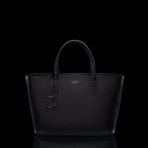 Von Baer Estelle black leather tote bag for women, shown from the front with structured top handles, pebbled leather texture, leather clochette and gold-tone logo.