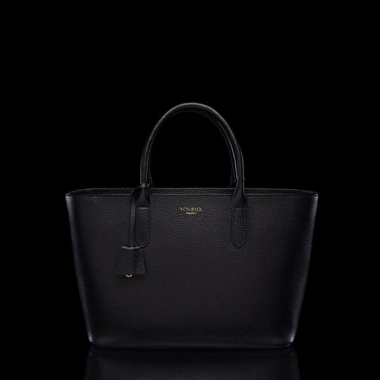 Von Baer Estelle black leather tote bag for women, shown from the front with structured top handles, pebbled leather texture, leather clochette and gold-tone logo.