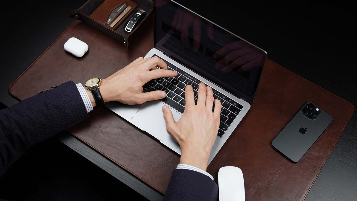 Von Baer Executive brown leather desk pad and laptop mat used by businessman in suit working on MacBook