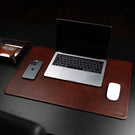 Von Baer Executive luxury leather desk pad in brown on a dark wood table with an open MacBook, iphone and mouse.