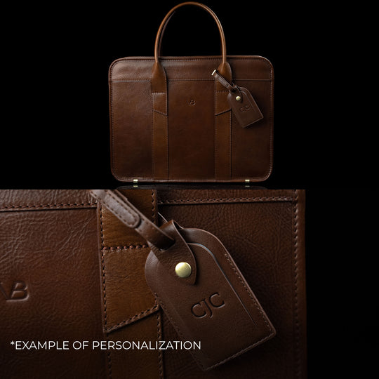 An exquisite Von Baer leather laptop bag showing an example of personalization with embossed initials on the attached luggage tag.