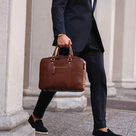 Handsome man in a suit holding a brown Von Baer luxury business leather laptop bag in Italy
