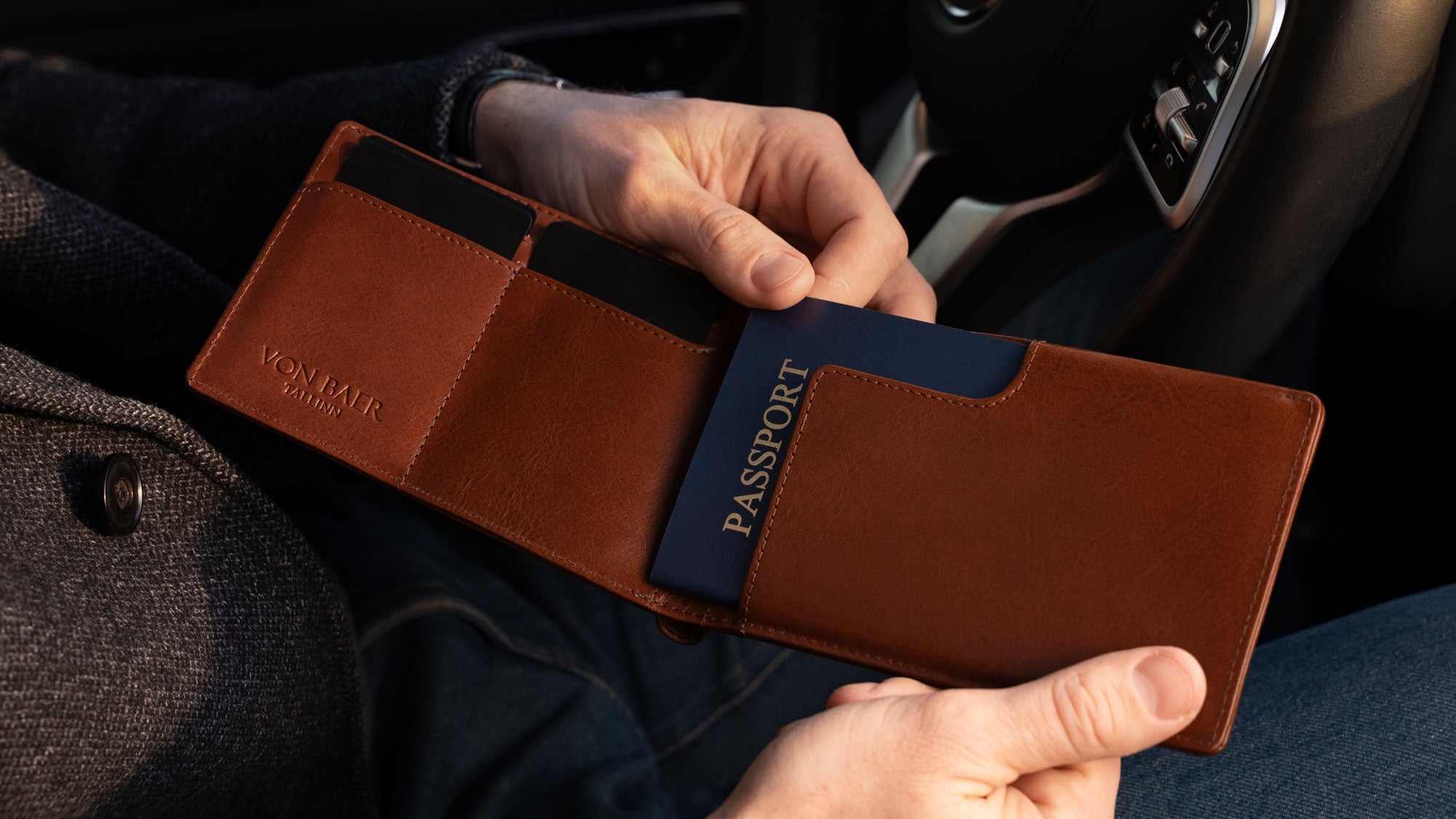 Von Baer Harrington large full-grain leather passport wallet in brown for travel, pulling out a US passport from the holder.