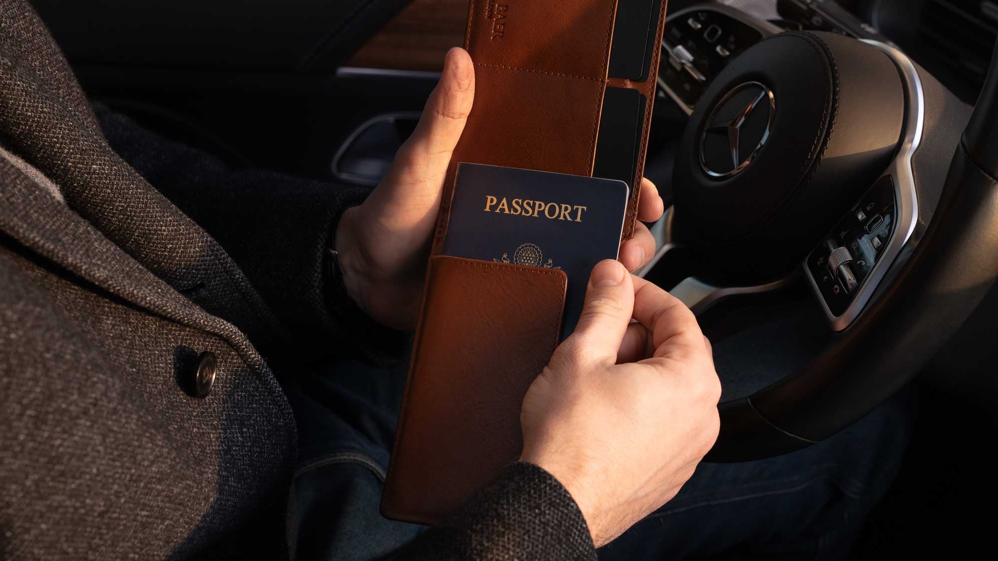 Von Baer Harrington large full-grain leather passport wallet in brown with US passport being pulled out inside a Mercedes.