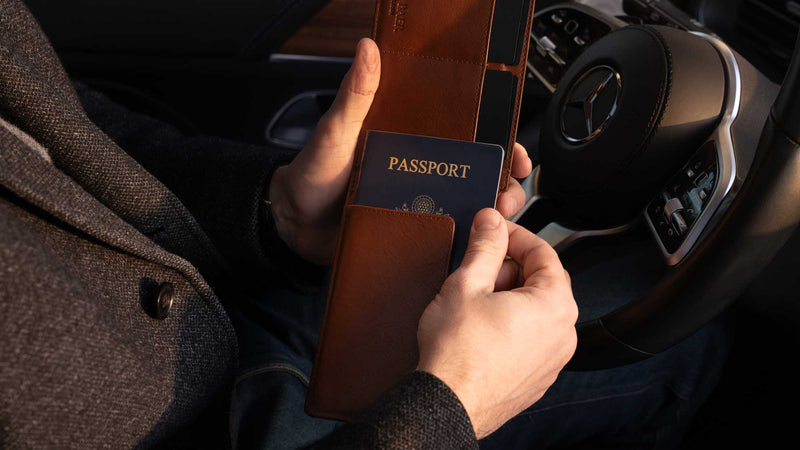 Von Baer Harrington large full-grain leather passport wallet in brown with US passport being pulled out inside a Mercedes.