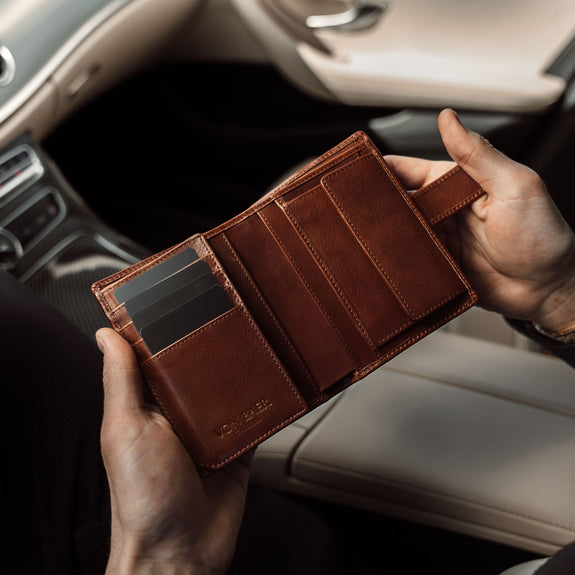Von Baer Heritage premium men's leather trifold wallet in solid brown, opened in the car.