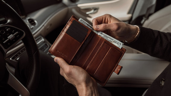 Von Baer Heritage premium men's leather trifold wallet in solid brown, with cash in the car, slider.