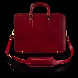 A red Von Baer leather shoulder bag strap is shown on a leather bag.