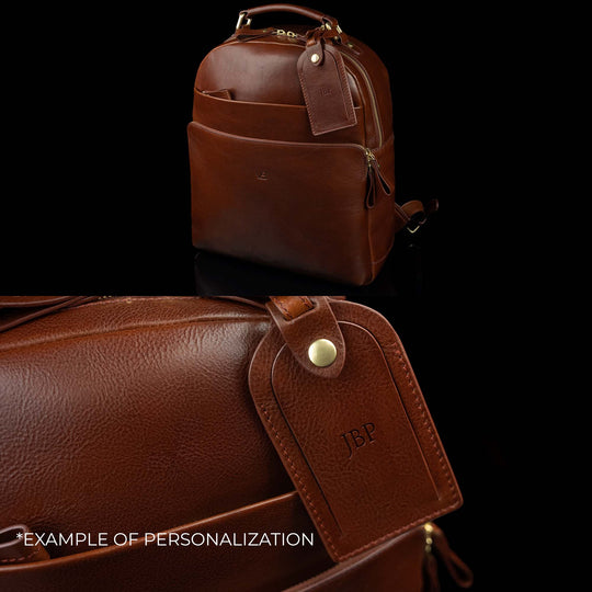 Luxurious Von Baer full-grain leather laptop backpack with a large luggage tag, showcasing an example of personalization with embossed initials