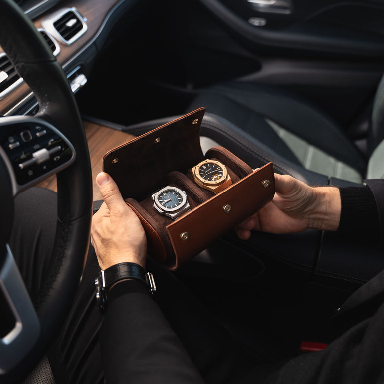 A man in a Mercedes car holding an opened brown Von Baer luxury full-grain leather watch roll case with two slots, showing watches inside.