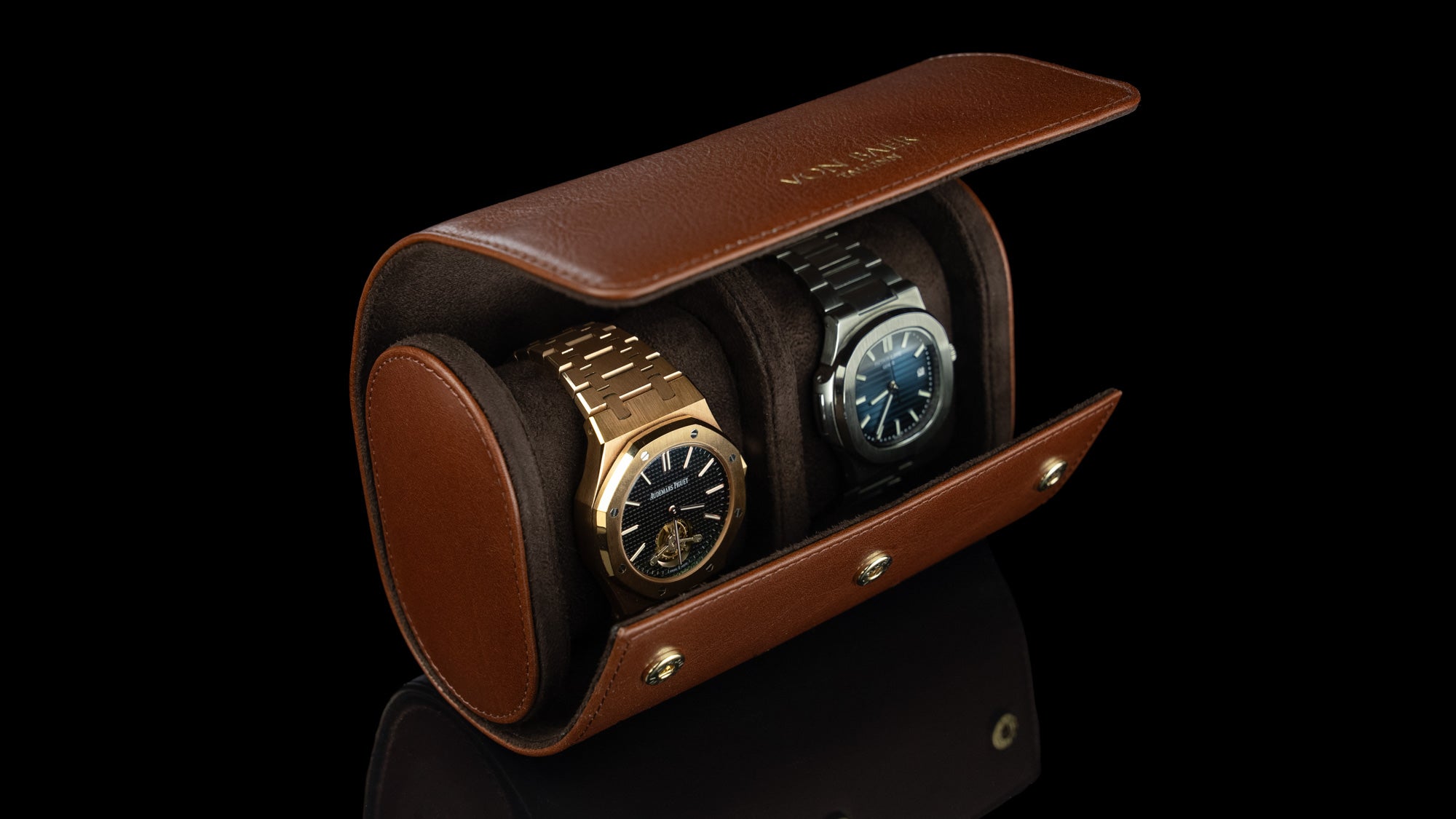 A brown Von Baer luxury leather watch roll with a Patek Philippe and an Audemars Piguet watch inside.
