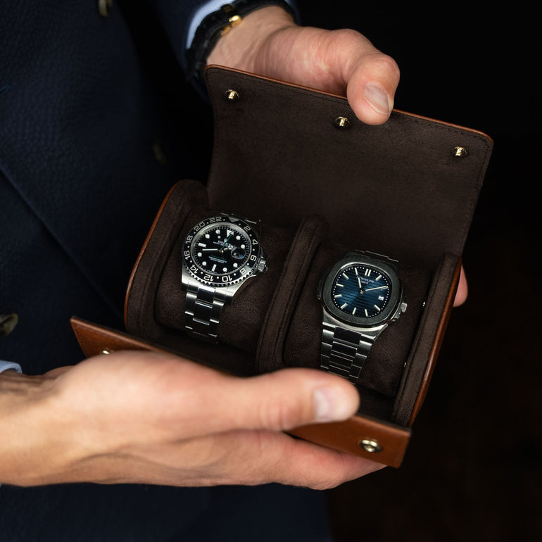 A brown Von Baer luxury quality leather watch roll with a Rolex and a Patek Philippe watch.